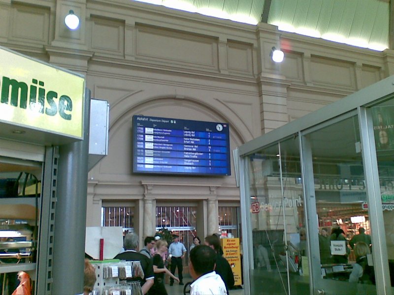 Halle (Saale) Hbf - Zuganzeiger in der Bahnhofshalle, die mit allerlei Verkaufsstnden vollgepfropft ist.