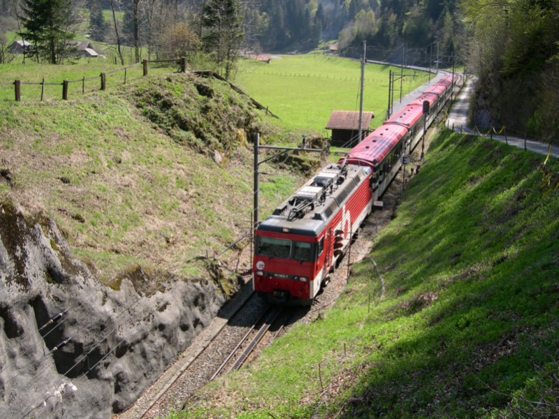 HGe 4/4 101 963-7 fhrt am 04.05.2006 mit ihrem IR nach Luzern nahe der aufgelassenen Station Kppeli in den gleichnamigen Tunnel ein. Es geht langsam voran, denn direkt vor dem Tunnel beginnt der Zahnstangenabschnitt bis Lungern. Der Kppelitunnel ist 146m lang und die Zge lassen sich an beiden Portalen direkt vom Wanderweg aus bequem fotografieren. Der gesamte Wanderweg Brnig Hasliberg-Lungern fhrt in unmittelbarer Nhe des Bahndamms der Strecke Meiringen-Luzern entlang.