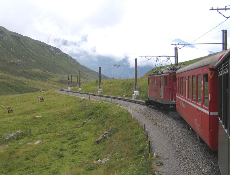 HGe 4/4 I FO 33 mit dem Nostalgie-Glacierexpress zwischen Oberalpsee und Nätschen. Als Fahrleitungsträger dienen am Oberalp je zwei Holzmasten. Sie haben Sollbruchstellen um sie nach Lawinenniedergängen ohne Schäden an den Fundamenten leichter wechseln zu können.  - 13. 08.2005
