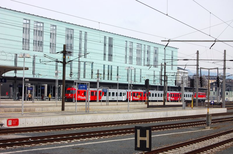 Hier eine imposante Ansicht des rechten Seitenflgels des Hauptbahnhofes Linz. Im Jahr 2004 wurde er nach Komplettumbau im Rahmen der sterreichischen Bahnhofsoffensive seiner Bestimmung bergeben. Die Fassade besteht zu 85 % aus gefrbtem Glas. Davor typisch fr die greren Stdte ein  City-Shuttle  mit seinem unverwechselbaren Design. 