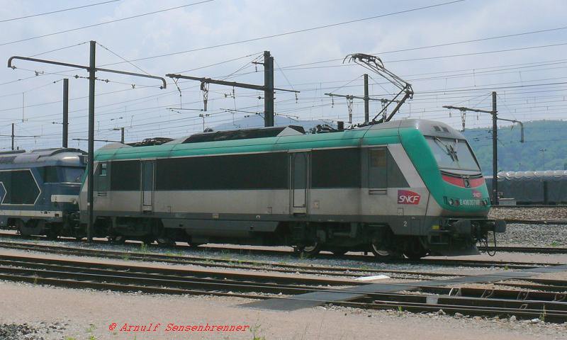 Hier steht die BB36357.

In den beiden Nachbarlndern Italien und  Belgien fhrt man jeweils mit 3000V =. Die SNCF lie nun die Baureihe BB36000 bauen, welche auch unter 3000V = fahren kann.
Sie ist eine Weiterentwicklung der BB26000  SYBIC  (SYnchrone Drehstrommotoren BICourant=Zweispannungsfhig). Die Reihe BB36000 heit  ASTRIDE . Sie hat als erste franzsische Ellokreihe ASynchrone Drehstrommotoren und ist fr TRI=drei Netzspannungen gebaut.

Beim genauen Hinschauen fllt einem auf, da sie an der Front einen roten Balken und die Nummer E436 357MF trgt.
Was soll das? Nun, die Lok ist nicht nur italienfhig, sondern  die SNCF haben sich auch eine italienische Tochtergesellschaft zugelegt und dazu einen Teil ihrer italienfhigen Lok auch in Italien zugelassen.
Fr eine allgemeine italienische Netzzulassung mu die Lok aber gem den italienischen Bestimmungen ber einen roten Warnstreifen und eine Loknummer nach dortigen Vorschriften verfgen. Flugs wurde also fr Italien die Betriebsnummer 36357 zur E436 357MF erweitert.

08.06.2007 Ambrieu Dpot 
