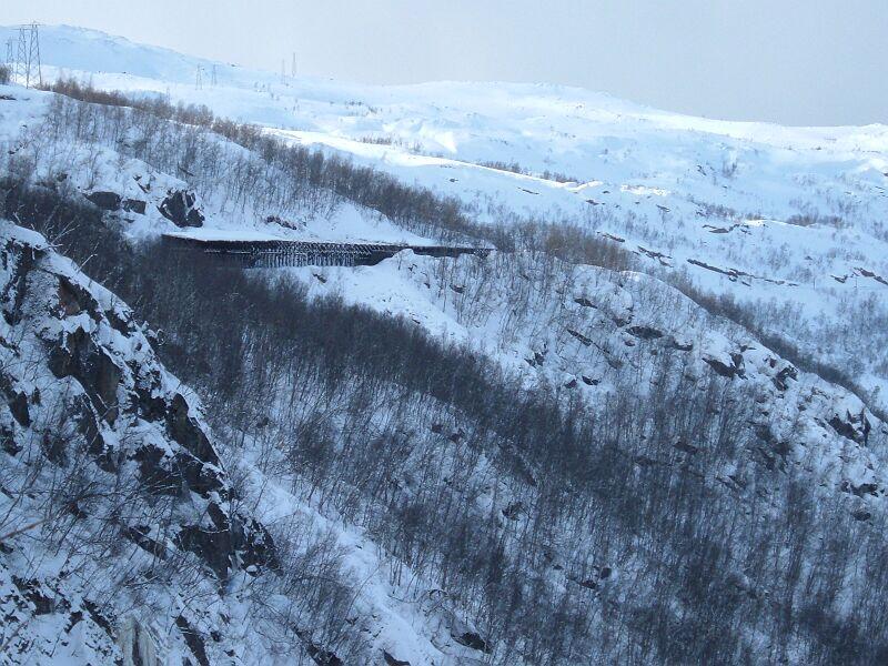 Hinter dem Tunnel in nrdlicher Richtung fhrt die Strecke bis Narvik immer am Hang entlang bis auf Meereshhe, teils in Schneegallerien. Zwischen Tunnel und erster sichtbarer Schneegallerie zweigt durch den Berg ein 2. Gleis ab und kommt nach dem sdlichen Tunnel wieder auf die alte Strecke, aufgenommen am 19.03.2006. 