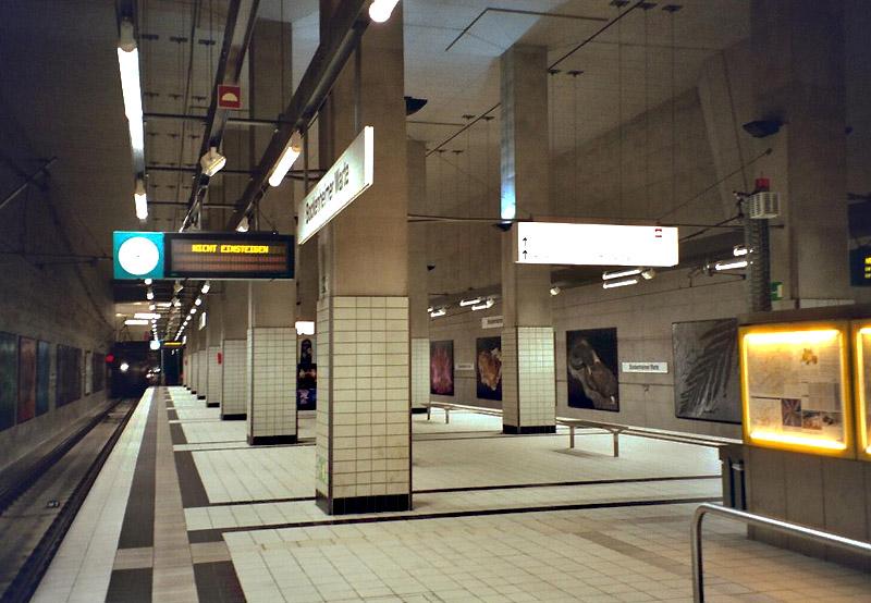 Hohe Halle mit zwei Stützenreihen -

Blick in die 2001 eröffnete hohe Bahnsteighalle der U4 an der Bockenheimer Warte. Der Bahnsteig befindet sich in der 3ten Tiefebene. Es besteht Übergang zu den hier kreuzenden Linien U6 und U7. Zudem besteht zwischen den beiden Tunnels eine Gleisverbindung. Architekten: Nieper und Partner. 

Analoge Aufnahme, 2003 (M)