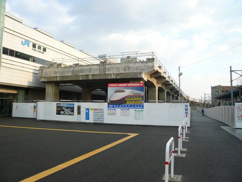 Hokuriku-Shinkansen: Bis jetzt erreicht der Shinkansen nur an den Endpunkten Niigata und Akita im Norden das Japanische Meer. Der im Bau stehende Hokuriku-Shinkansen wird den ganzen Raum um die Städte Toyama, Kanazawa und Fukui ans Hochgeschwindigkeitsnetz anschliessen. Hier das schon gebaute Hochtrassee in Fukui; das Plakat erklärt:  Der Hokuriku-Shinkansen eröffnet uns die Zukunft - Bau des Hochtrassees Fukui-Bahnhof , und gross:  Mit unseren vereinten Kräften bringen wir den Shinkansen zum Fahren!  Fukui, 4.November 2008.