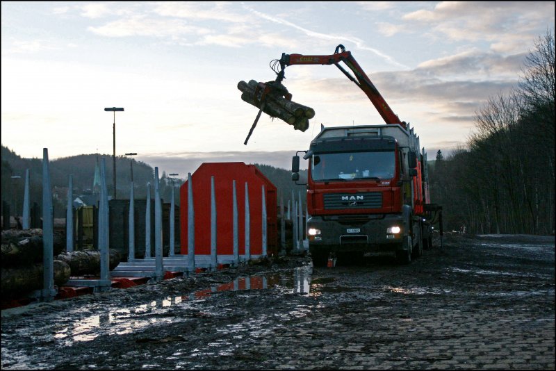 Holzumschlag mit Sonnenuntergang und den Schweizer im Sauerland: Der Fahrer des MAN TGA verldt in den Abendstunden des 07.02.2008 in Brgge (Westf) seine Ladung Stammholz auf Fabrikneue(?) Rnoos644.