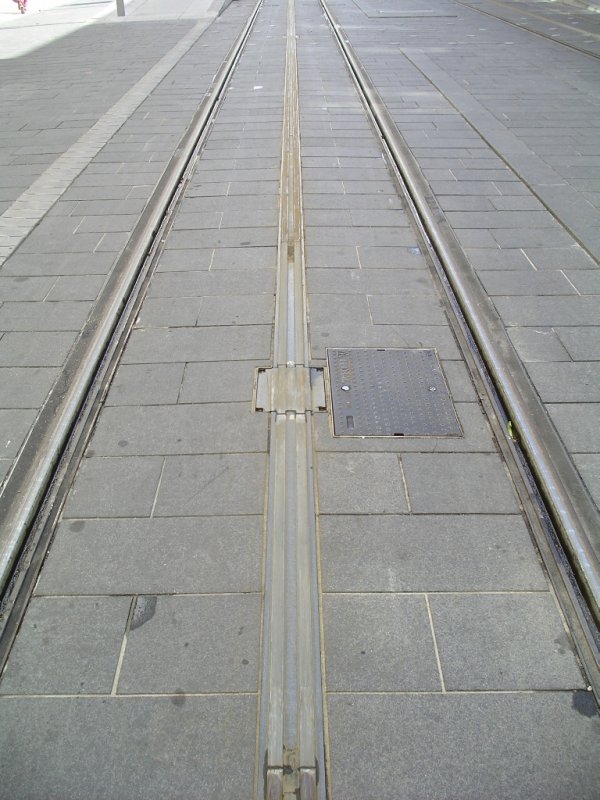 In der Altstadt von Bordeaux wollte man bei der Wiedereinf�hrung der Stra�enbahn  unter allen Umst�nden eine Oberleitung vermeiden. Daher gibt es nur auf den Au�enstrecken eine Oberleitung. 
In der Innenstadt gibt es das Mittelleitersystem APS (Alimentation par Sol).
Das System besteht aus jeweils 8 Meter langen Stromschienen,die nur  dann unter Strom gesetzt werden, wenn ein Zug dar�ber f�hrt.
So ist das Betreten der Schiene in der Mitte gefahrlos m�glich.
Die Z�ge haben jeweils zwei Schienenschleifer (�hnlich wie bei M�rklin) zur Stromabnahme.
Das System funktioniert allerdings nicht ohne Probleme.

19.09.2004
Bordeaux

