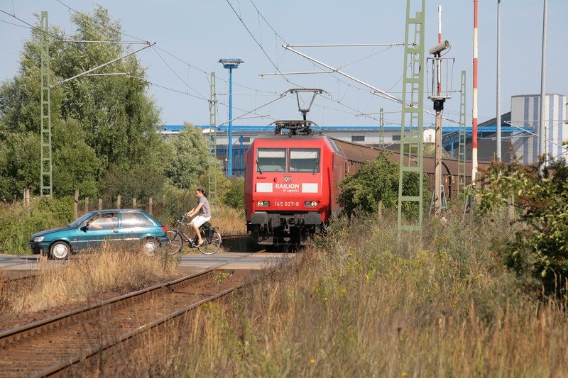 In der Poeler Strae in Wismar steht schon die 145 027-9 mit ihrem Gterzug bereit. Gleich werden sich die Schranken schlieen und die Fahrt aus dem Seehafen frei geben. 25.07.2008