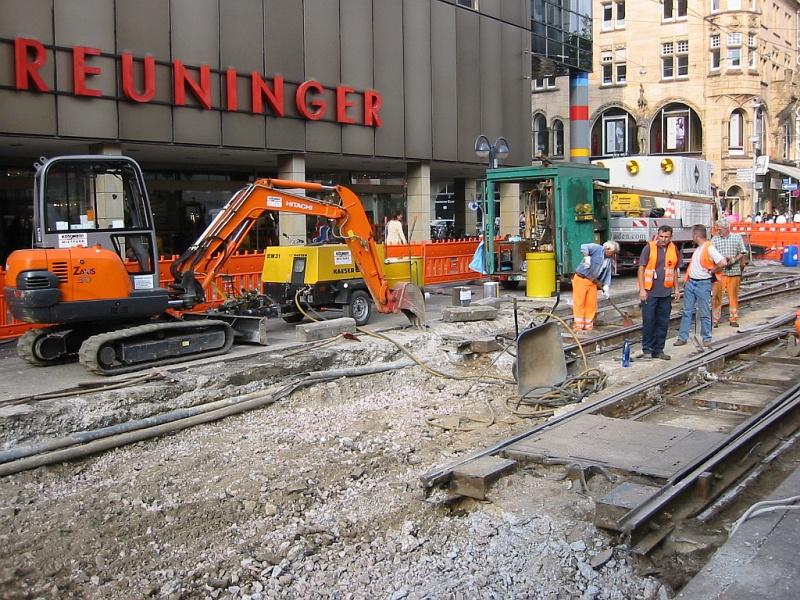 In den Sommerferien 2005 wurden wieder Straenbahngleise in der Karlsruher Innenstadt gewechselt, hier am Europaplatz. Die Folge waren wieder umfangreiche Umleitungen. Die Aufnahme stammt vom 23.08.2005. Die alten Gleise sind entfernt worden, jetzt beginnt die Bearbeitung des Untergrunds. Die im Bild sichtbaren Weichenteile blieben liegen; das Gleisdreiecke am Europaplatz war schon vor einiger Zeit erneuert worden.