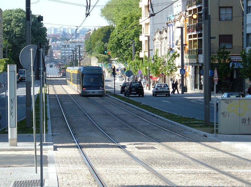 In Vila Nova de Gaia fhrt die Metro bis zur Endstation Joao de Deus auf eigenen Gleiskrper zwischen der beiden Straenfahrbahnen. An der nchsten Kreuzung mu der Autoverkehr nach links oder rechts abbiegen, im Hintergrund die Dom-Luis-Brcke mit der Einfahrt zur  Unterwelt , dahinter die City von Porto.
