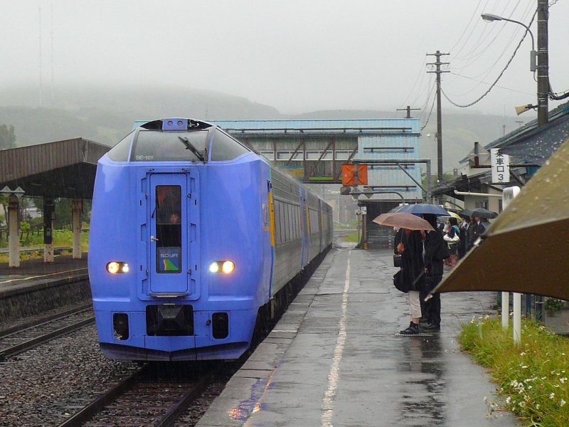 KIHA 261: Der erste Morgenzug für die 5-stündige Fahrt nach Süden mit Wagen KIHA 261-101 an der Spitze fährt bei strömendem Regen in Minami Wakkanai (Wakkanai Süd) ein. 28.August 2008. 