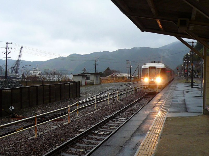 KIHA 85 (キハ８５): Die beiden Endwagen dieser Triebwagenzüge sind unsymmetrisch; Richtung Norden haben sie (wie im Bild) Uebergänge, an die Zusatzmodule gefügt werden können. Bild: Durchfahrt eines Zuges in Kata, einer Bucht am Pazifik. 24.Februar 2009.