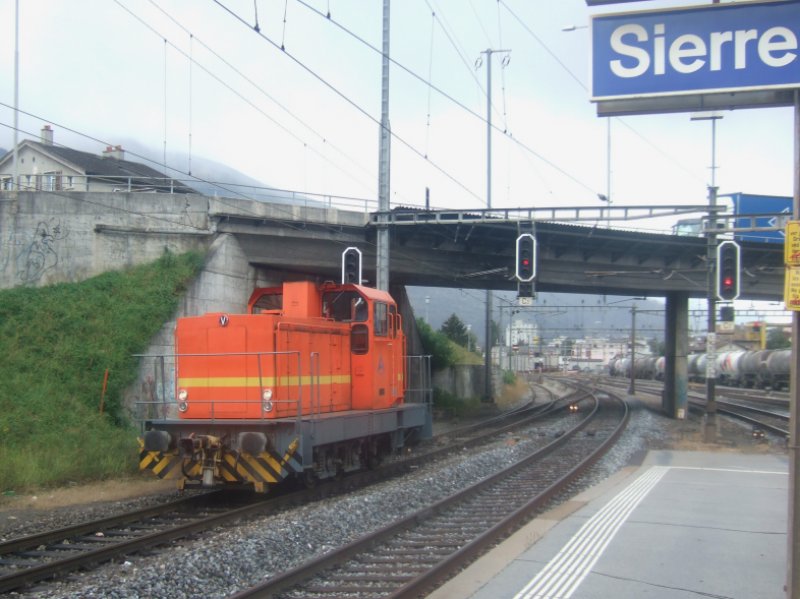 klein, orange: Am 12.10.09 rangiert eine private Diesellok im Bahnhof Sierre. Die Bahnhofstafel hatte gerade noch Platz.
