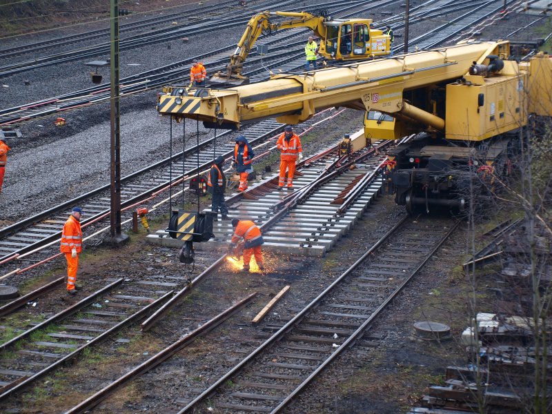 Knochenjob bei schlechtem Wetter, Gleisarbeiter  beim zusammenbau einer Doppelkreutzweiche am Aachener Westbahnhof.