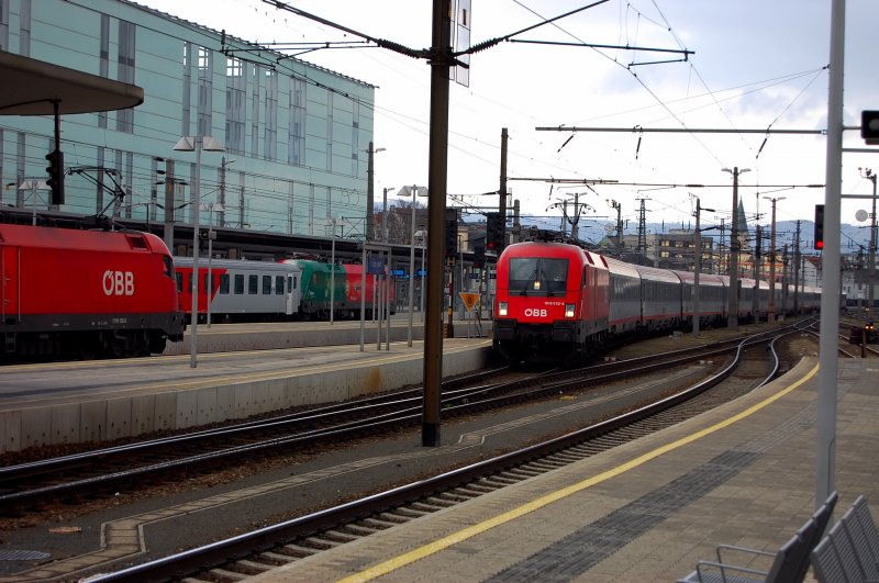 Kurz vor einem heftigen Regenschauer bringt 1016 032-3 einen Eurocity unter das rettende Bahnsteigdach. Bedrohlich das Licht aber treffend fr die Farben. Links ein noch auf Fahrgste wartender  City-Shuttle  mit dem  Portugal-Stier .