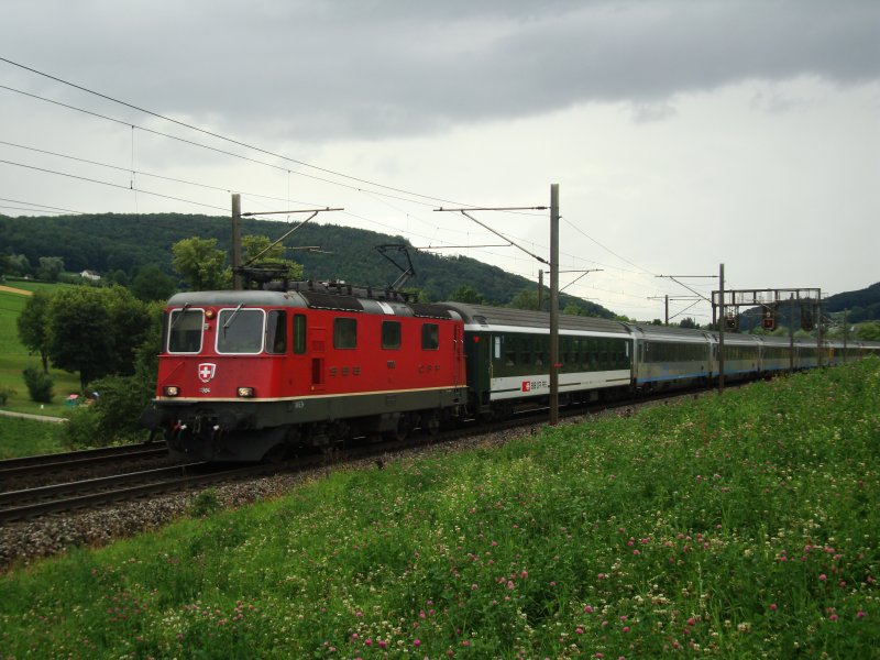 Kurz vor einem Regengutsch ist die Re 4/4 II 11304 mit ihrem EC nach Milano am 08.07.2008 zwischen Gelterkinden und Tecknau unterwegs.