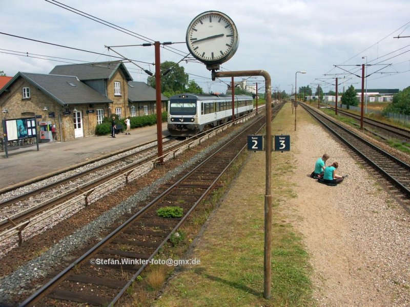 Landstation Taulov anders umgesetzt. Ein MR Richtung Kolding hlt gleich am Hausbahnsteig. Auf dem wie frher aussehenden Mittelbahnsteig haben sich zwei Jugendliche Niedergelassen um auf den Zug Richtung Fredericia zu warten... Juli 2009