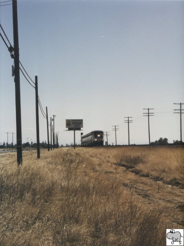 Langsam nhert sich ein Zug der Amtrack California. Als Zuglok dient eine F 59 PHI. Das Bild entstand am 07. September 2002 an einer Landstrae in Kalifornien/ USA.