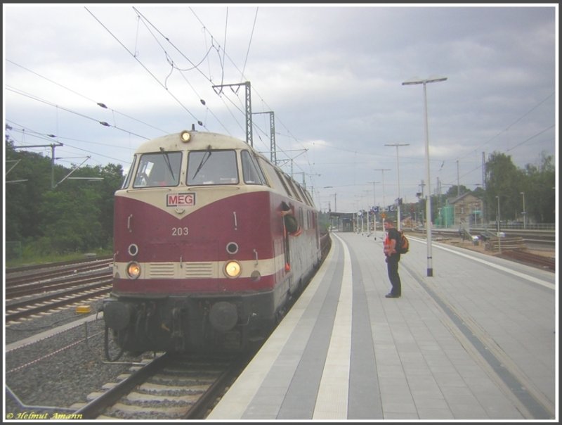 Lok 203 der MEG (ex BUNA 203) stand am 21.07.2007 mit einem Schotterwagenzug aus Flachwagen fr die Gleisbauarbeiten an der Strecke am Flughafen Regionalbahnhof im Bahnhof Frankfurt am Main-Stadion. Der Halt dort erfolgte offenbar nur zur Mitnahme zweier Tf, die am Bahnsteig standen.