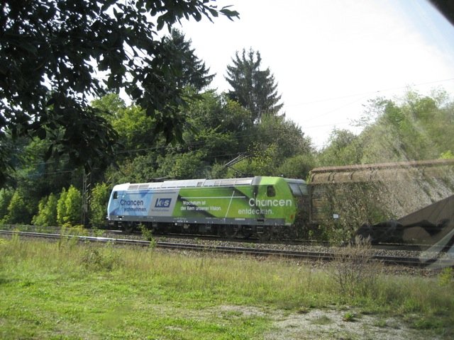 Lok der Reihe 185 mit Reklame von k+s zieht am 11.September ´08 einen Güterzug  - u.a. mit auf Flachwagen verladenen Kleinlaster - um 14 Uhr 15 gen Süden auf der KBS 982 ( gen Donauwörth ), vorbei am aufgelassenen H-Punkt bei Möhren.
