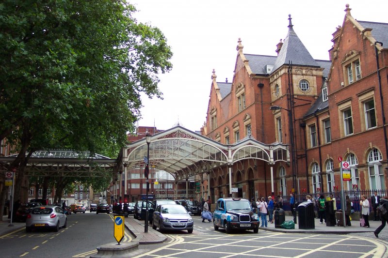London Marylebone Station - Vorplatz
Die Marylebone Station wurde 1899 erffnet und ist die jngste der Londoner Hauptbahnhfe. Am Anfang war es auch noch eine unwichtigsten, so wurde beim Bau die Anzahl der Gleise um die Hlfte reduziert. 
Erst mit der Verlegung von mehreren berregionalen Zgen von Paddington nach Marylebone Ende der 80er wurde der Verkehr aufgewertet. 
Heutzutage wird die Station von Chiltern Railways betrieben (neben Blackfriars der einzige, der nicht von National Rail betrieben wird), die sehr erfolgreich von dort aus nach Wycombe, Stratford-upon-Avon, Birmingham oder Kidderminster operiert. Ausserdem befindet sich dort eine Umsteigemglichkeit zur Tube (Bakerloo Line). Der Bahnhof ist heutzutage mit jhlich 11.6 Millionen Passagieren der am schnellsten wachsende Bahnhof Londons.