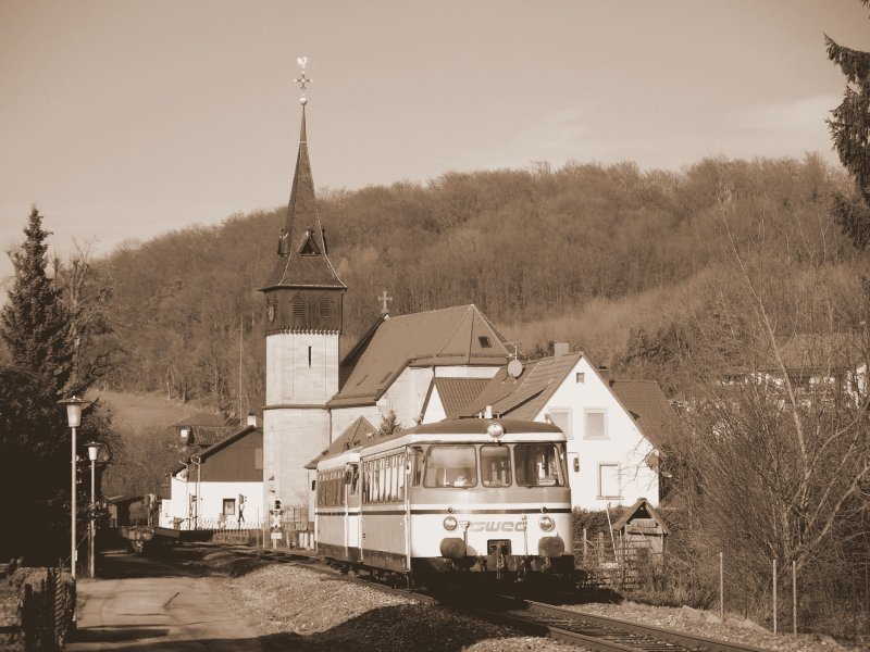 MAN VT 27 und VS 142 mit dem ersten und zugleich vorletzten Zug des Tages als SWE 70773 von Neckarbischofsheim Nord nach Hffenhardt am bekannten Kirchenmotiv in Untergimpern, einem kleinen Dorf im Schwarzbachtal, welches durch die Nebenbahn geteilt wird.