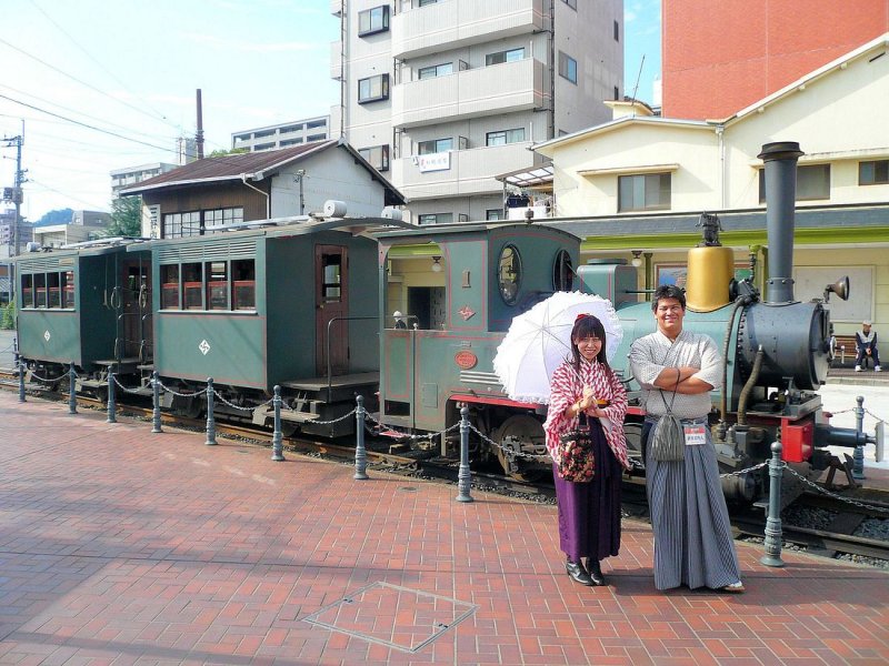 Matsuyama Strassenbahn, die Bocchan-Zge: Beim Aussteigen in Dgo Onsen (die Heissen Quellen von Dgo) wird man von diesen flotten jungen Leuten in Empfgang genommen, die fr ihr Stdtchen mit seinen kleinen Geschften, Boutiquen und natrlich den traditionellen Bderanlagen werben. Sie wnschten, zusammen mit dem Zug Lok 1 + Wagen 1 + Wagen 2 (urspr. 1888, nachgebaut 2001) aufgenommen zu werden. 18.September 2009.