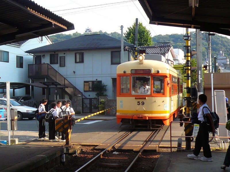 Matsuyama Strassenbahn, Serie 51-61: Wagen 59 fhrt in die Station Takasago-ch ein. Wiederum ist die Burg der Frsten von Matsuyama oben auf dem Berg zu sehen. 18.September 2009.