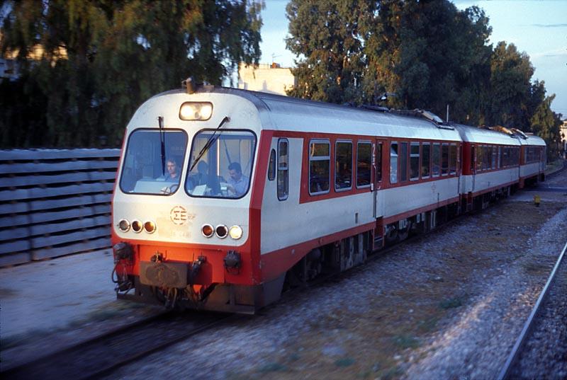 Meterspur-IC von Patra unterwegs zwischen Athen Peloponn. und Pireas.
Leider war die Wagennummer nicht mehr zu erkennen. Fotografiert aus dem letzten Wagen eines Zuges aus Chalkida, vermutlich zum letzten Mal. Am 5.04.diesen Jahres sollte die Regelspurstrecke von Athen nach Krinthos in Betrieb gehen, die Meterspur wurde bis dorthin zurckgezogen.
Korrektur: Die Regelspurstrecke ist bis Krinthos in Betrieb, abschnittsweise nur eingleisig. An 3 Stellen zwischen Megara und  Kinta liegt das Meterspurgleis wegen Platzmangel in der Achse des zuknftigen Gleises Krinthos - Athen. Wie es jetzt aussieht, bleibt die Meterspur zwischen Agii Anarjiri und Patra in Betrieb, bis die NBS fertiggestellt ist. Der neue Bf Krinthos hat 2 Gleise fr die Meterspur, eins davon ist ein Dreischienengleis. Angebunden wird aber nur die Strecke Richtung Argos , Nafplion und Kalamata. Der Bf Athen Peloponn. ist seit dem 5. September 2005 auer Betrieb und vollkommen gleislos.
