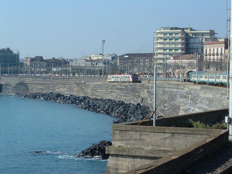 Metrozug hat den Bahnhof Catania C verlassen in Richtung City und Catania-Borgo, rechts ein Nahverkehrszug der FS, der von einer Diesellok in den Personenbahnhof geschoben wird (04.02.2006).