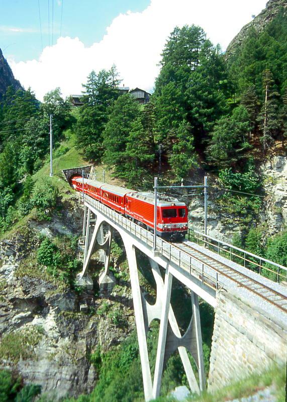 MGB BVZ GLACIER-EXPRESS C 904 von Zermatt nach St.Moritz am 10.06.1995 auf Mhlebach-Viadukt mit Zahnrad-E-Lok HGe 4/4II 5 - B 2285 - B 2286 - A 2076 - FO AS 4024 - RhB B 2425 - RhB B 2283. Hinweis: BVZ und FO-Fahrzeuge noch in alter Lackierung!
