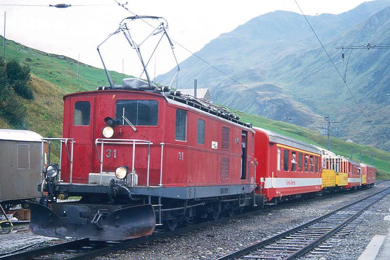MGB FO-AUSSICHTSWAGENZUG 1339 fr RHTIA INCOMING von Disentis nach Realp am 08.09.1994 in Ntschen mit Zahnrad-E-Lok HGe  4/4I 31 - A 4063 - RhB B 2095 - RhB B 2097 - B 4268 - RhB B 2098 - D 4343 - D 4341. Hinweis: Fotofahrt ber Oberalppass mit Bernina-Aussichtswagen bei Dauerregen!  Die zwei D am Zugschluss wurden als Bremswagen in den 110-Promille-Rampen bentigt, da die Berninawagen keine Bremszahnrder haben. 
