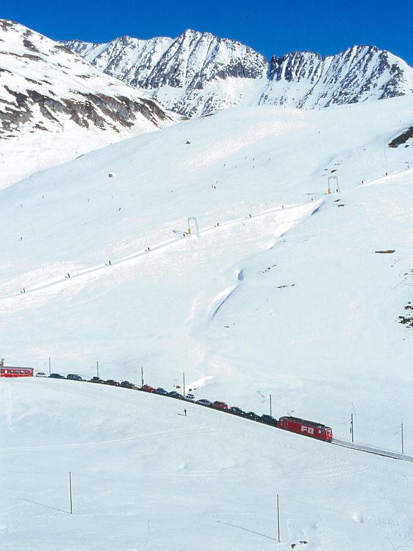 MGB FO-AUTOTRANSPORTZUG 4334 Von Andermatt nach Sedrun am 14.02.1998 kurz nach Oberalppasshhe mit Zahnrad-E-Lok HGe 4/4II 108 - 5x Rw - RhB B 2213. Hinweis: Lok noch in alter Lackierung, hier ist ein bis auf den letzten Platz ausgelasteter Autozug am Oberalppass eingesetzt. Bei nur 130 Tonnen Vollast sind solche Transporte nicht ganz billig. Trotzdem wird die Umwelt geschont und bei nur ein oder zwei Autostunden Fahrzeitersparnis die Bahn bentzt.
