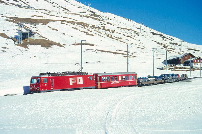 MGB FO-AUTOTRANSPORTZUG 4335 von Sedrun nach Andermatt am 15.02.1998 etwa 300m unterhalb Ntschen mit Zahnrad-E-Lok HGe 4/4II 105 - RhB B 2213 - Sklv 4833 - Rvw 4798 - Sklv 4834 - Sklv 4832. Hinweis: Lok noch in alter Lackierung.
