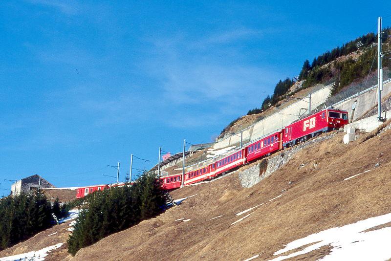 MGB FO-ENTLASTUNGSZUG 2347 von Disentis nach Andermatt am 15.02.1998 zwischen Biel-Kehrtunnel und Butzen-Kehrtunnel mit Zahnrad-E-Lok HGe 4/4II 104 - RhB B 2212 - B 4268 - ABt 4195 - RhB B 2255 - B 4263 - D 4342. Hinweis: FO-Fahrzeuge noch in alter Lackierung.
