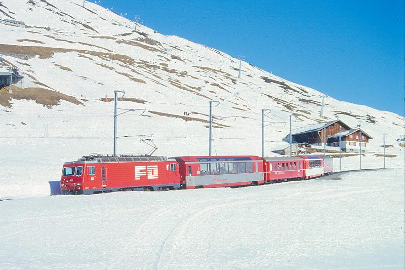 MGB FO-GLACIER-EXPRESS 903 von St.Moritz nach Zermatt am 15.02.1992 etwa 300m unterhalb Ntschen mit FO-Zahnrad-E-Lok HGe 4/4II 101 - BVZ AS 2011 - RhB B 2423 - FO AS 4021 - RhB WR 3815. Hinweis: FO/BVZ-Fahrzeuge und Speisewagen in alter Lackierung.
