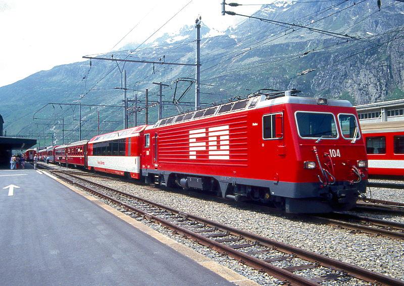 MGB FO-GLACIER-EXPRESS C 904 von Zermatt nach Davos Platz/St.Moritz am 01.06.1993 in Andermatt mit FO-Zahnrad-E-Lok HGe 4/4II 104 - FO AS 2025 - RhB B 2425 -  RhB WR 3815 - BVZ AS 2013 - RhB B 2426 - BVZ B 2284 - FO A 4066 - FO ABt 4194 - FO HGe 4/4II 106. Hinweis: Ankuppeln des Speisewagens als 3. Wagen vom kreuzenden Glacier-Express 903.
