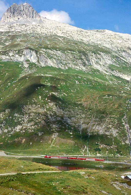 MGB FO-GLACIER-EXPRESS G 903 von Davos Platz nach Zermatt am 05.09.1997 am Oberalppass/Oberalpsee mit FO-Zahnrad-E-Lok HGe 4/4II 104 - FO PS 4013 - FO Br 4293 -  RhB B 2450 - RhB B 2423 - FO AS 4023 - RhB WR 3815. Hinweis: gut vorstellbar sind bei den hohen steilen Berghngen im Winter regelmig groe Lawinen-Abgnge. Deshalb ist hier die Bahnstrecke wo ntig, mit kilometerlangen Galerien wintersicher ausgebaut.FO-Fahrzeuge noch alte Lackierung!

