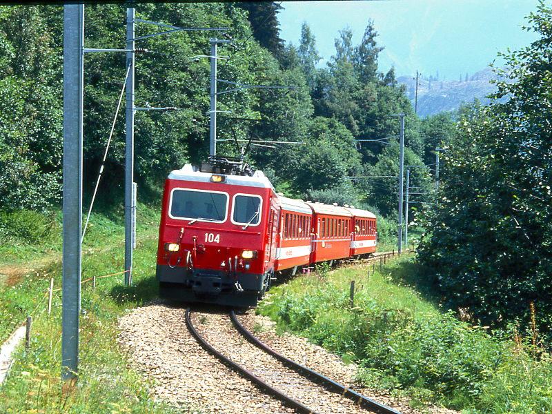 MGB FO-GLACIER-EXPRESS H 20903 von Chur nach Zermatt am 04.08.1992 bei Mompe Tujetsch mit FO-Zahnrad-E-Lok HGe 4/4II 104 - FO B 4266 - RhB B - FO B 4272. Hinweis: dies ist ein Glacier-Express fr Gruppen, der so bis 28.05.1994 verkehrte. Fahrzeuge noch alte Lackierung!

