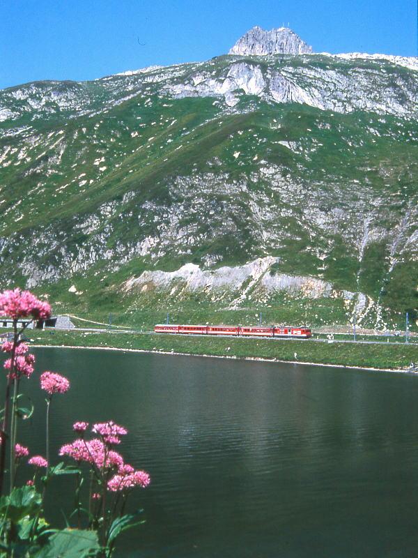 MGB FO-REGIONALZUG 239 von Gschenen nach Disentis am 07.08.1992 auf Oberalppass mit Zahnrad-Triebwagen Deh 4/4II 96 - B 4285 - B 4286 - ABt 4181. Hinweis: Fahrzeuge noch in alter Lackierung, Blick ber Oberalpsee.
