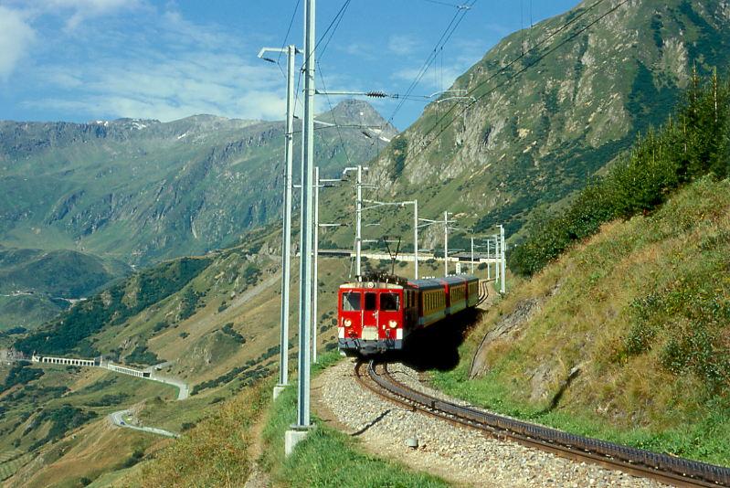 MGB FO-REGIONALZUG 326 von Andermatt nach Disentis am 24.08.1997 bei Tschamut-Selva mit Zahnrad-Triebwagen Deh 4/4II 92 - B 4279 - B 4280 - ABt 4157.Hinweis: Zug bremst sich in der langen Zahnstange im 110-Promille-Geflle vom Oberalppass herab und hat die im Hintergrund sichtbare Calmot-Galerie verlassen. Links ist das Quellgebiet des Vorderrheins. Unten ist die Passstrae zum Oberalp sichtbar.
