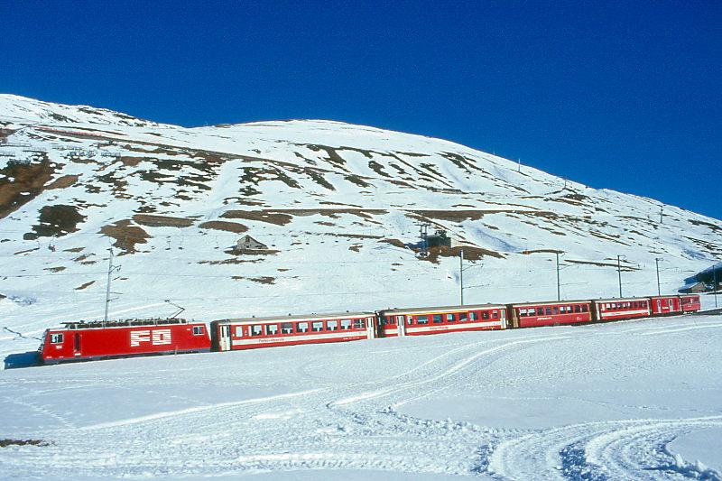 MGB FO-REGIONALZUG 327 von Disentis nach Andermatt am 15.02.1998 kurz unterhalb Ntschen mit Zahnrad-E-Lok HGe 4/4II 104 - B 4268 - ABt 4195 - RhB B 2252 - B 4260 - D 4342 - RhB B 2260. Hinweis: FO-Fahrzeuge noch in alter Lackierung. Zug bremst sich hier in einen 4193m langen Zahnstangenabschitt mit 110 Promille Geflle von Ntschen nach Andermatt hinab. 28er Weitwinkelaufnahme.

