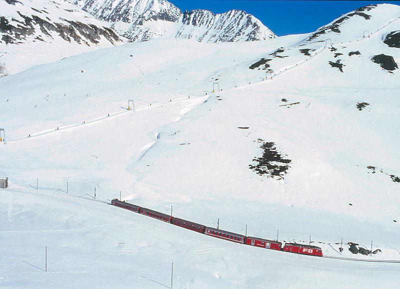 MGB FO-REGIONALZUG 336 von Andermatt nach Disentis am 14.02.1998 kurz nach Oberalppasshhe mit Zahnrad-E-Lok HGe 4/4II 101 - D 4341 - B 4264 - RhB B 2255 - ABt 5159 - B 2266. Hinweis: FO-Fahrzeuge noch in alter Lackierung, links ist das Ende der Oberalppass-Galerie zu sehen.
