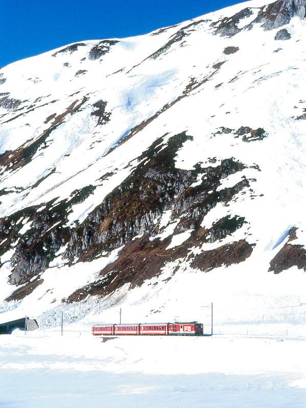 MGB FO-REGIONALZUG 549 von Gschenen nach Disentis am 14.02.1998 kurz vor Oberalppasshhe-Calmot mit Zahnrad-Triebwagen Deh 4/4II 93 - B 4281 - B 4282 - ABt 4151. Hinweis: FO-Fahrzeuge noch in alter Lackierung, links ist das Ende der Oberalpsee-Galerie zu sehen. Bei genaueren hinsehen ist gut zu erkennen, warum die Galerie fr einen sicheren Winterbetrieb zwingend ntig ist.
