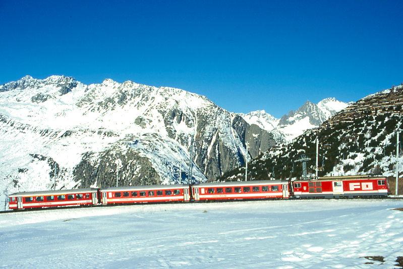 MGB FO-SPORTZUG 828 von Andermatt nach Oberalppass-Calmot am 15.02.1998 kurz vor Ntschen mit Zahnrad-Gepcktriebwagen Deh 4/4II 92 - B 4279 - B 4280 - ABt 4157. Hinweis: FO-Fahrzeuge noch in alter Lackierung.
