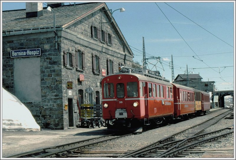 Mit 2253 m/.M. ist Ospizio Bernina die hchste Station der RhB und der hchste Eisenbahnbergang ber die Alpen. Im Juni 1985 war es schon so warm, dass ABe 4/4 35 bereits einen offenen Aussichtswagen mitfhrte. Dass der Winter noch nicht lange vorbei war, zeigen aber die Schneehaufen neben dem Stationsgebude. (Archiv 06/85)