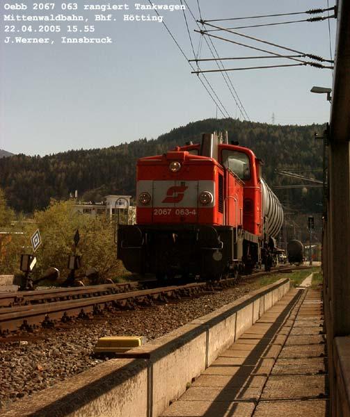 Mittenwaldbahn: 2067-063 rangiert Tankwagen beim Bahnhof Htting, einen der abgestoenen Wagen sieht man hier im Hintergrunde. Vorne, links der Lok, sind die geschickt montierten Schilder, die das Ende der Fahrleitung ber den Weichen zu den Abstellgleisen verknden, zu sehen. Der Schatten rechts ist das Gelnder der Brcke ber den Frstenweg, Httinger Au. 22. April 2005