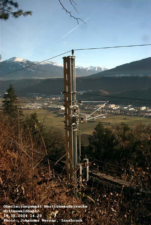 Mittenwaldbahn: hier besteht das Fundament des Bahndamms bereits aus solidem Fels, der sthlerne Mast ist fest mit demselben verschraubt, im Tal zu sehen Vls mit seinen ckern, im Hintergrund der Patscherkofel und der Eingang des Wipptals. 10. Dezember 2004