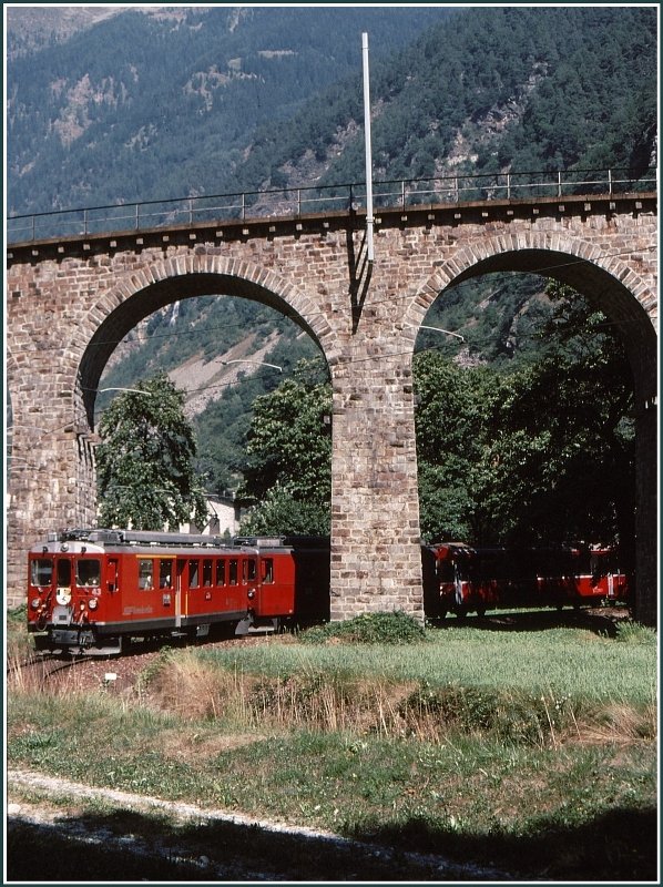 Nach der 360Grad Kurve ber das Kreisviadukt von Brusio erscheinen die zwei ABe 4/4 II mit dem Bernina Express zwischen Edelkastanienbumen in der unteren Brckenffnung. (Archiv 09/89)