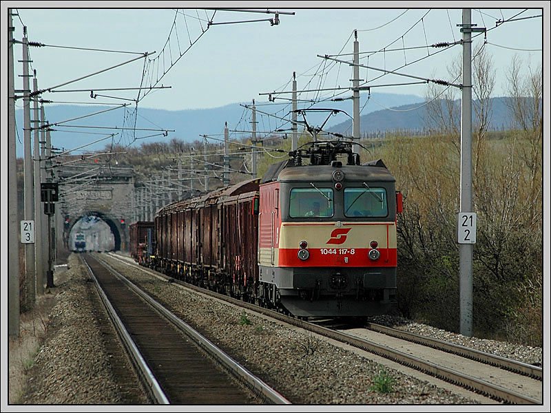 Neben 1044 092 hat nur noch 1044 117 eine Schachbrettlackierung. Die Aufnahme zeigt 1044 117 mit dem Gterzug 44404 von Spielfeld-Stra nach Wien Zvbf-Einfahrgruppe am 18.3.2007. Die Aufnahme wurde von der S-Bahnhaltestelle Gumpoldskirchen aus gemacht. Im Hintergrund ist das Nordportal des  Busserltunnels  zu sehen.