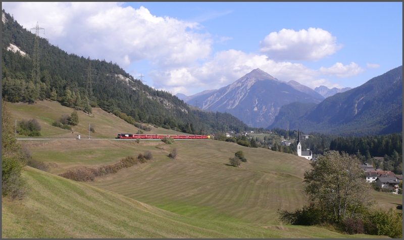 Neben der Kirche von Surava und vor der markannten Kulisse der Muchetta 2623m fhrt RE1144 aus St.Moritz talwrts. Zuglok ist Ge 4/4 III 648  Susch . (01.10.2009)